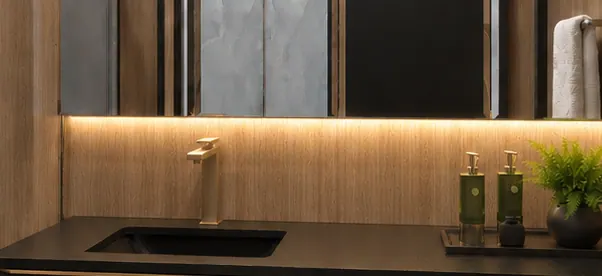 Detalhe: vão iluminado sob o espelho do banheiro, com a torneira e os itens de higiene sobre a bancada.